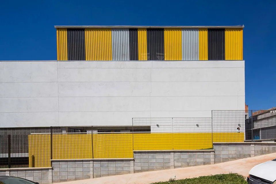 Um prédio branco com uma cerca amarela e um céu azul ao fundo.