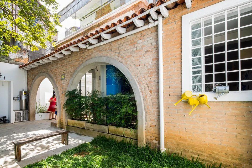 Um prédio de tijolos com arcos e um banco na frente.