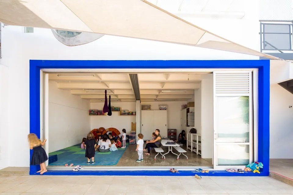 Um grupo de crianças brinca em uma sala com borda azul.