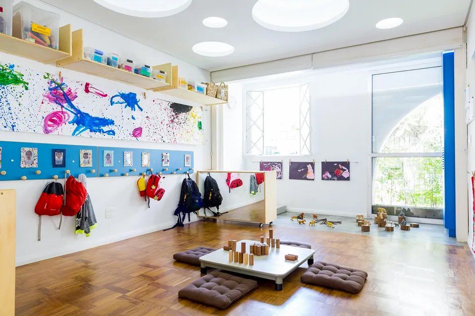 Uma sala com uma mesa e muitos brinquedos no chão.