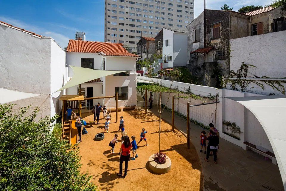 Um grupo de crianças brinca em um playground em frente a um prédio.