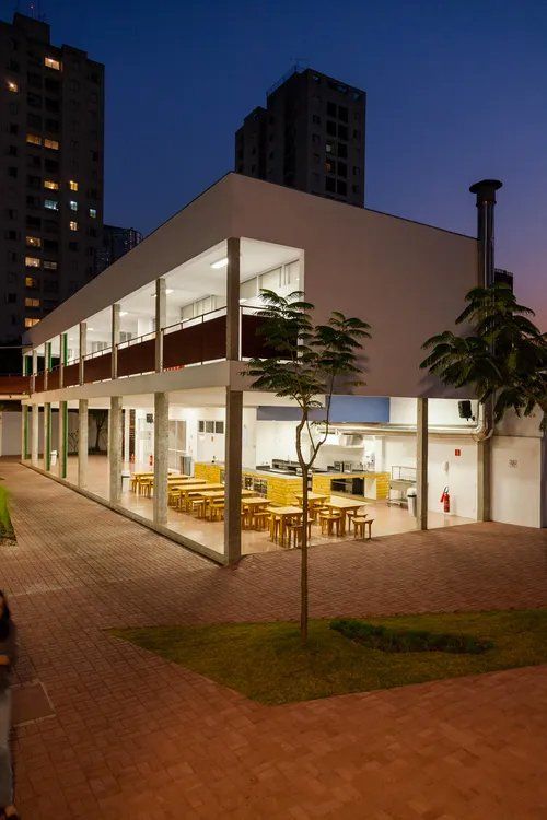 Um grande edifício com mesas e cadeiras na frente dele