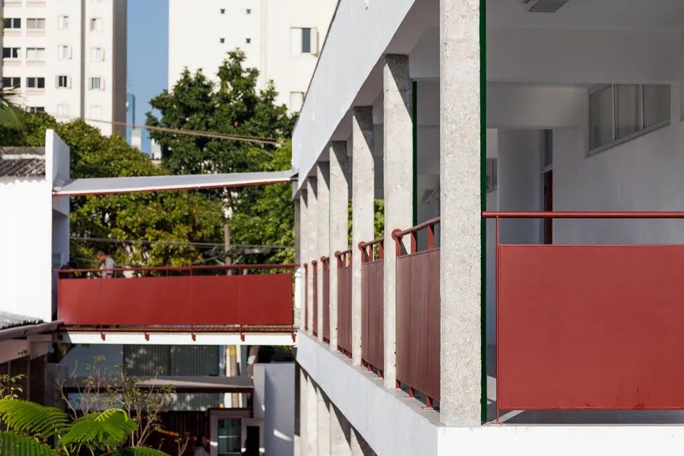 Um prédio branco com uma grade vermelha e uma ponte