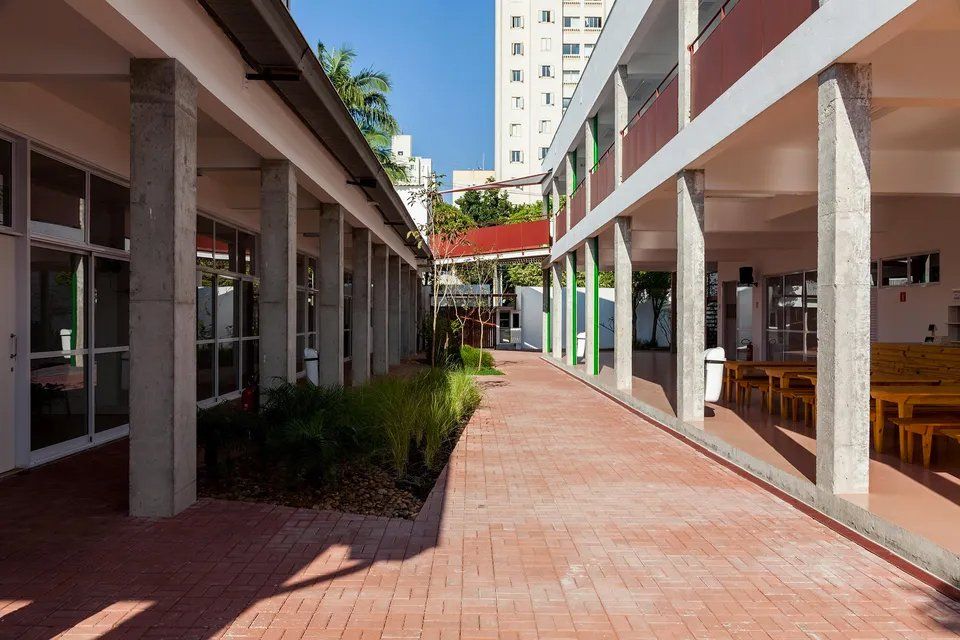 Um longo corredor entre dois edifícios com mesas e cadeiras