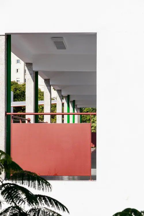 Um prédio com uma parede vermelha e uma grade verde