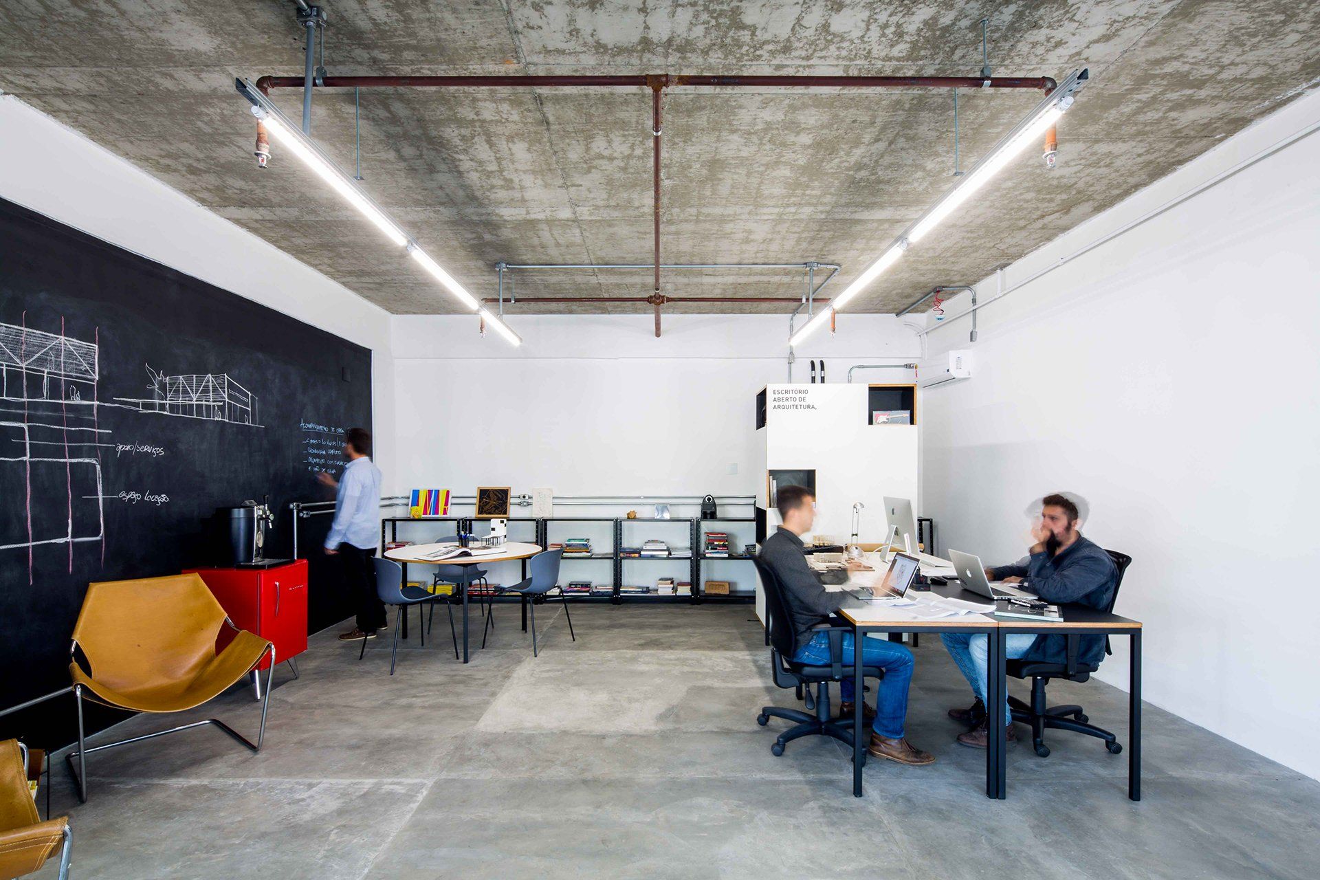 Um grupo de pessoas está sentado em mesas em um escritório.