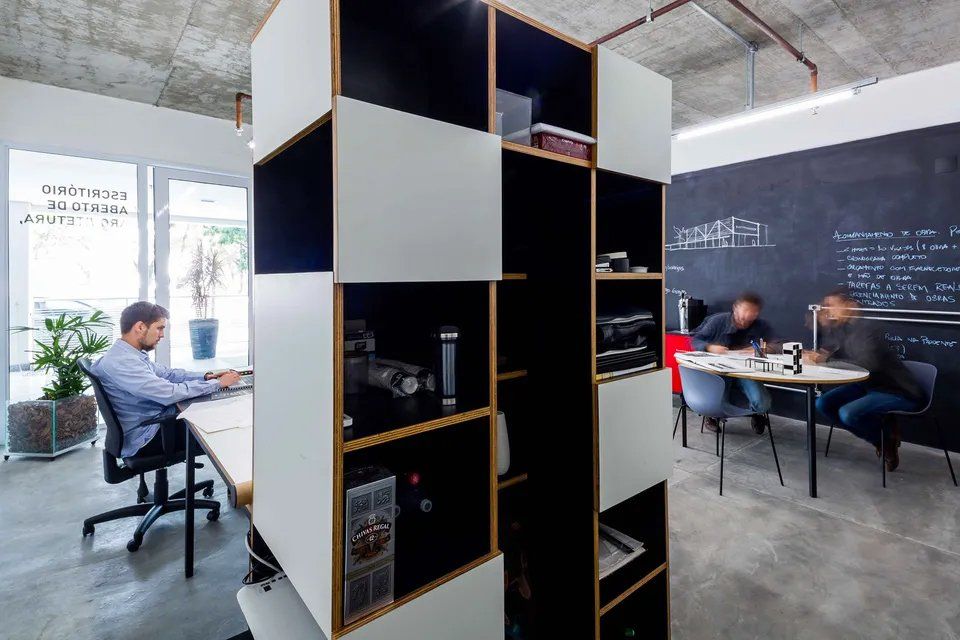 Um homem está sentado em uma mesa em um escritório trabalhando em um laptop.