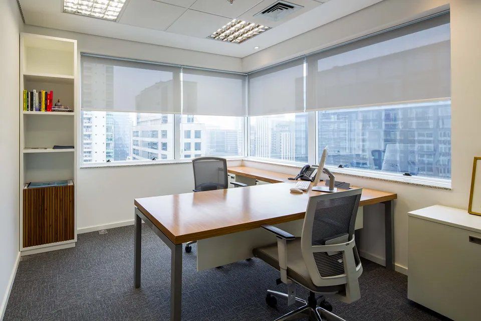 Um pequeno escritório com mesa e cadeira e uma grande janela.