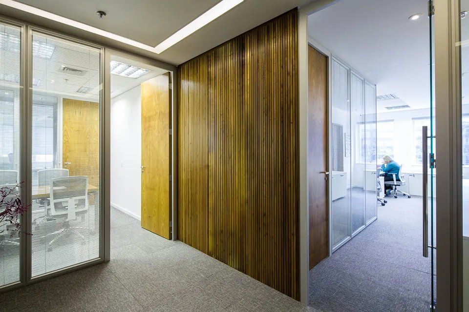 Um corredor em um prédio de escritórios com paredes de madeira e portas de vidro.