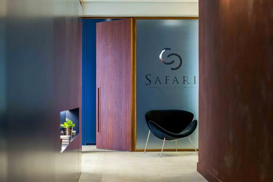 Uma cadeira preta está sentada em frente a uma parede de vidro com a palavra safari nela.