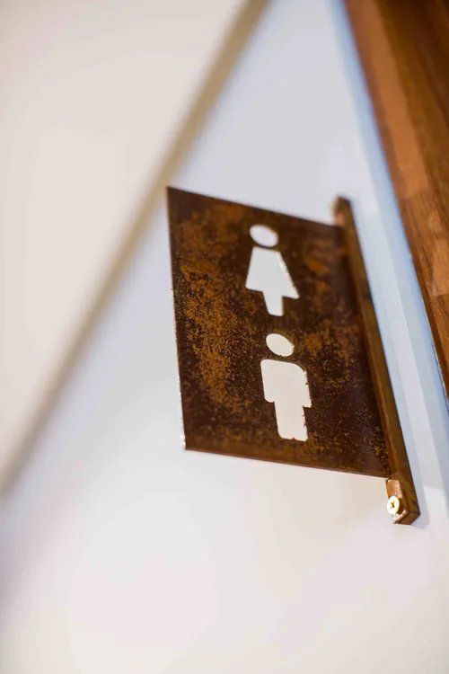 Um close de uma placa de banheiro na parede.