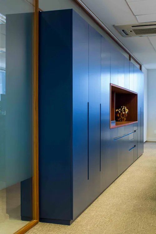 Um longo corredor com armários azuis e uma porta de vidro.
