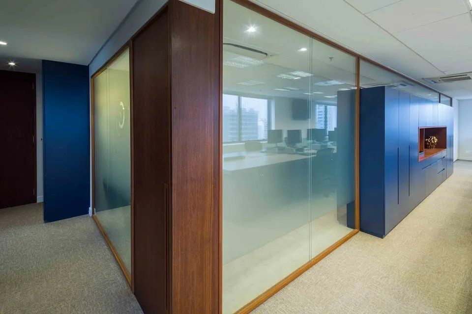 Um corredor de um escritório com parede de vidro e paredes de madeira.