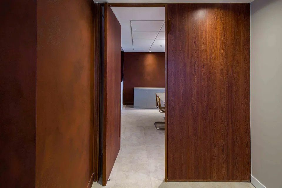 Um corredor com uma porta de madeira que leva a uma sala de conferências.