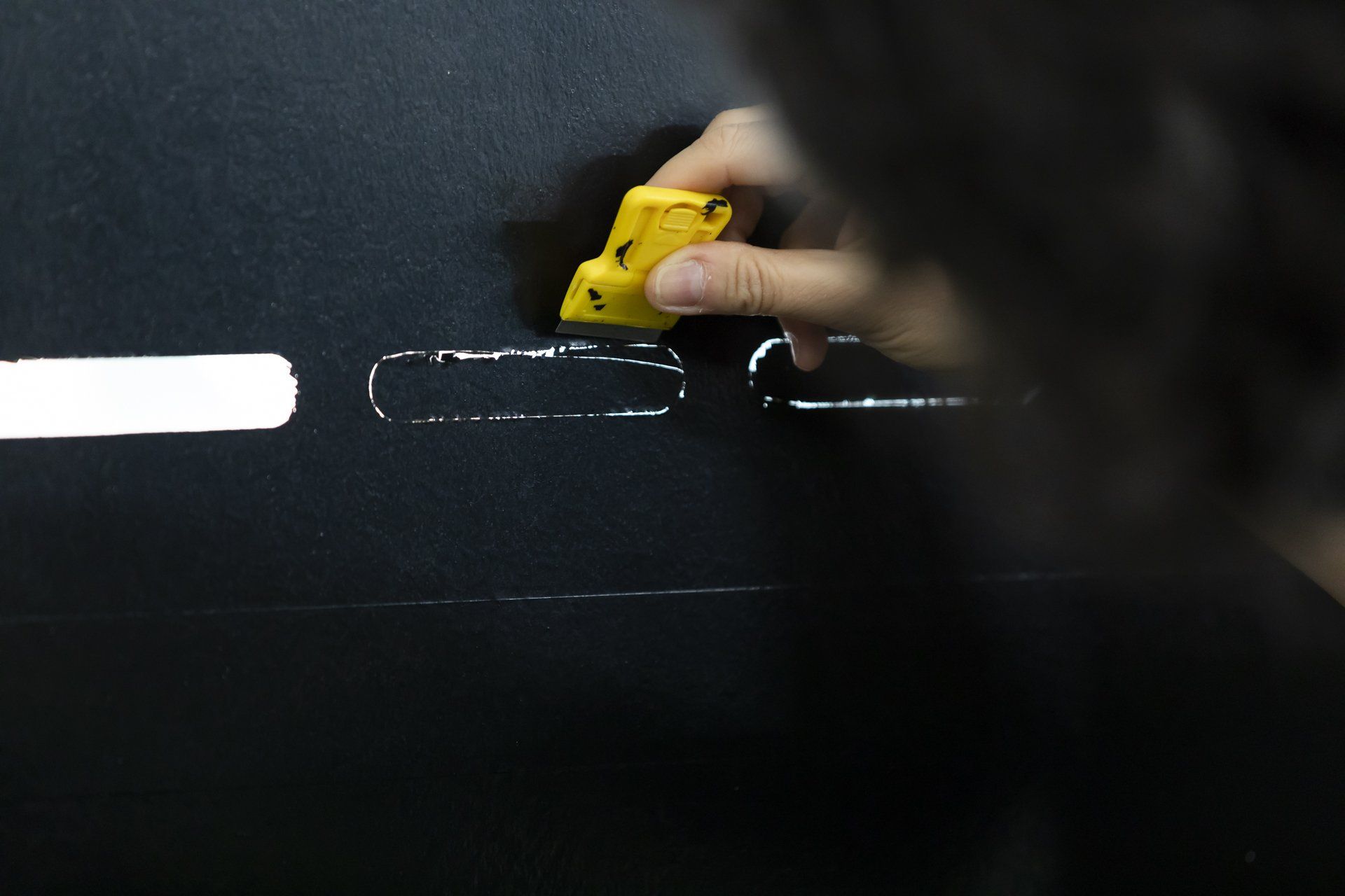Uma pessoa está usando uma borracha amarela em uma superfície preta
