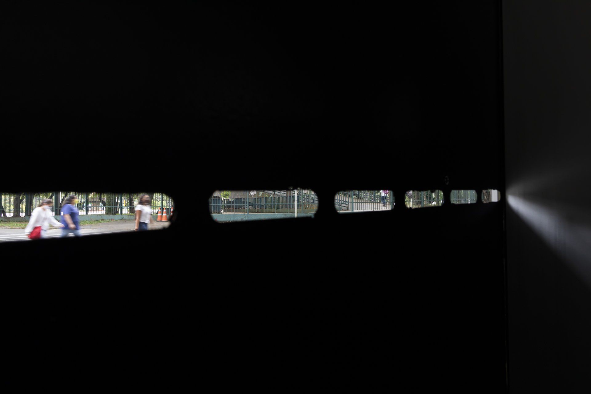 Um grupo de pessoas está andando em um quarto escuro através de uma janela.