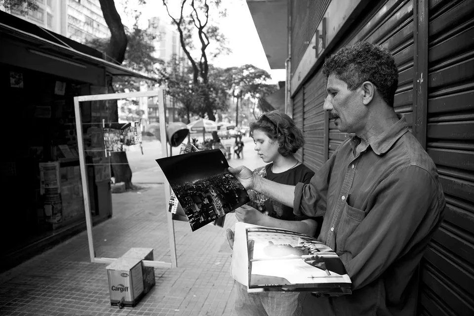 Um homem e uma mulher estão olhando uma foto na calçada