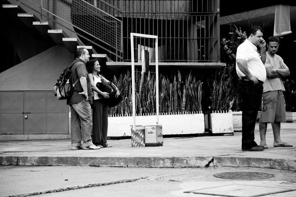 Uma foto em preto e branco de um grupo de pessoas em pé na calçada