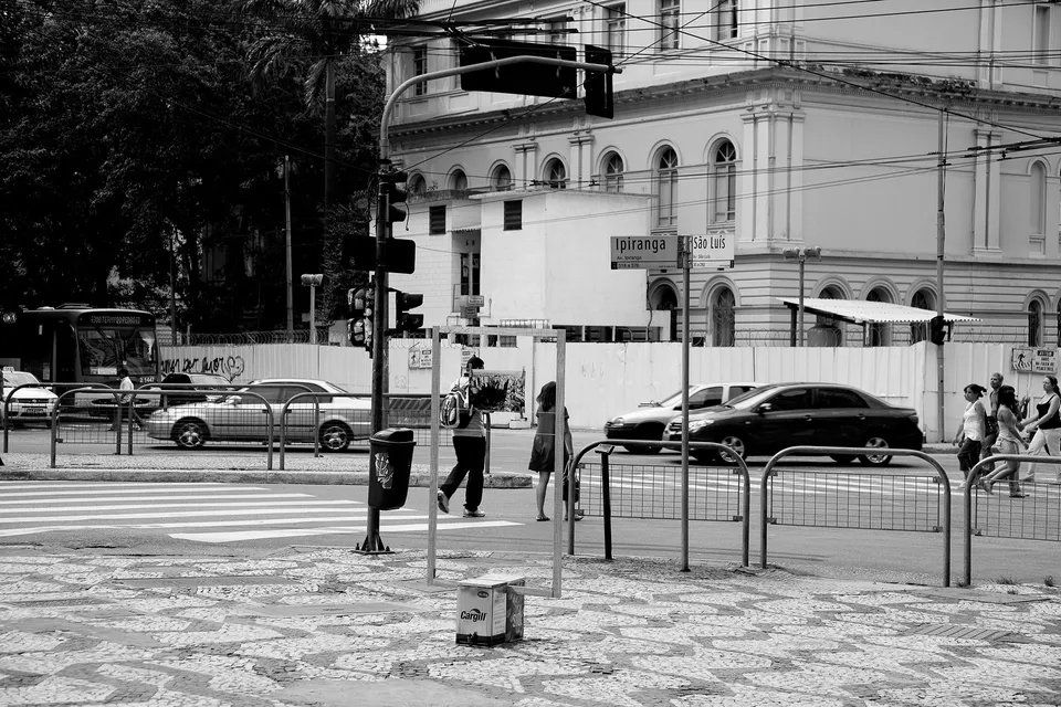 Uma foto em preto e branco de pessoas atravessando uma rua