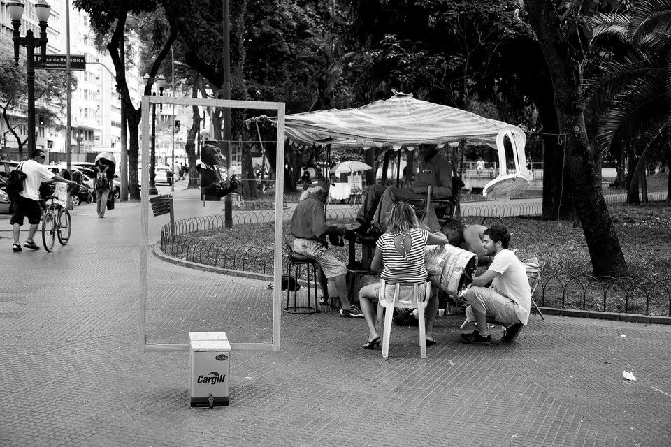 Um grupo de pessoas está sentado ao redor de uma mesa em um parque.