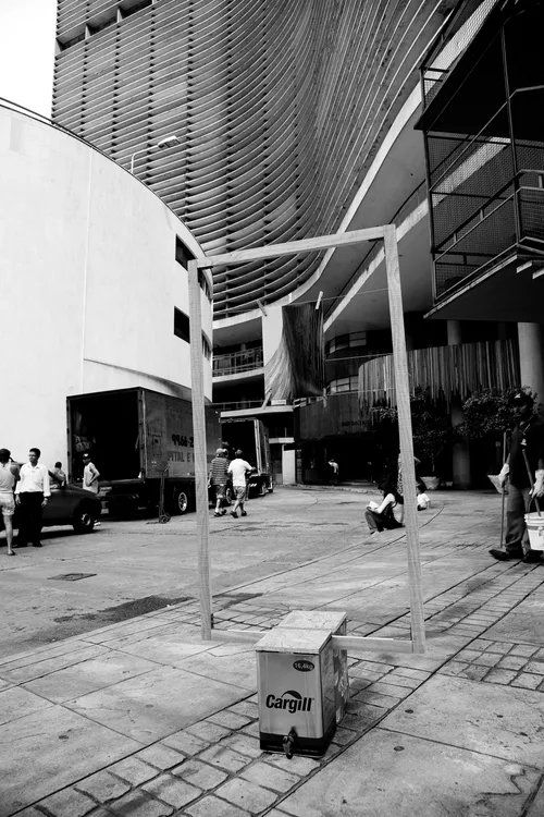 Uma foto em preto e branco de um prédio com uma lata de lixo em primeiro plano