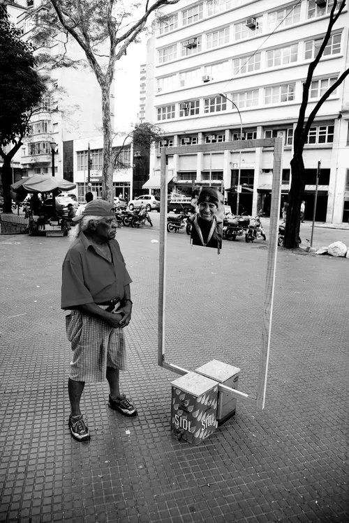 Uma foto em preto e branco de um homem parado em frente a um prédio
