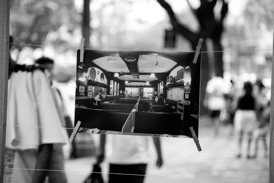 Uma foto em preto e branco de um prédio com pessoas andando ao fundo