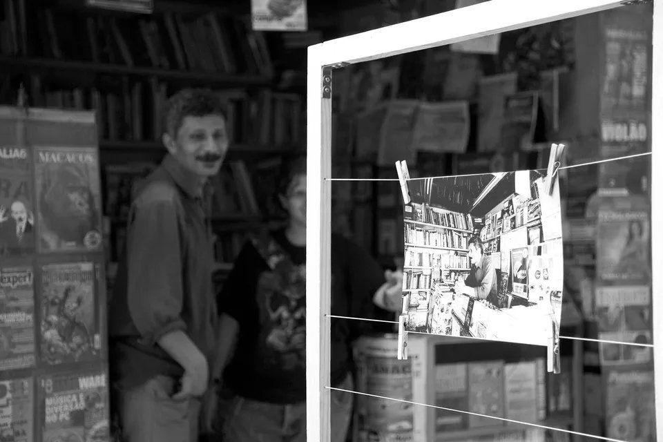 Uma foto em preto e branco de um homem parado em frente a uma livraria.