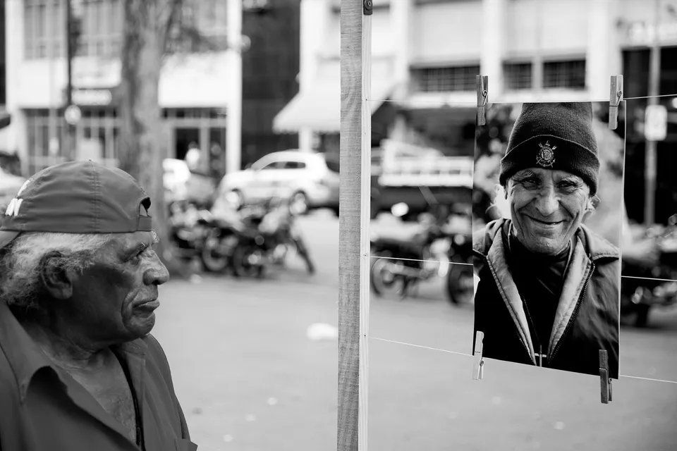 Uma foto em preto e branco de um homem parado ao lado de uma foto sua.