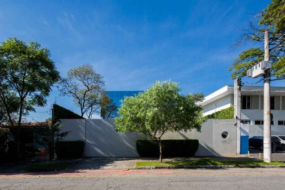 Uma casa branca com árvores na frente em um dia ensolarado.