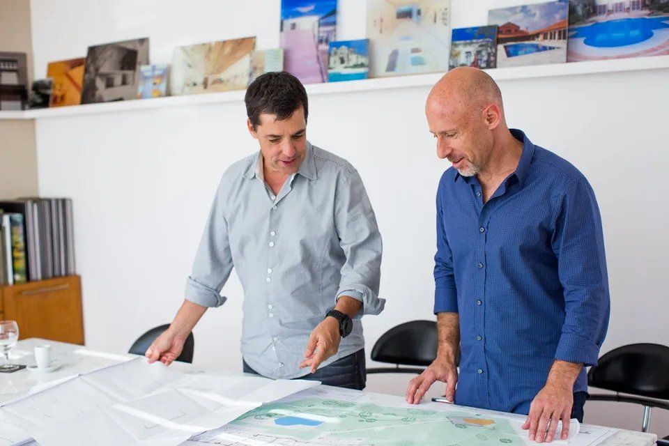 Dois homens estão olhando um mapa sobre uma mesa.