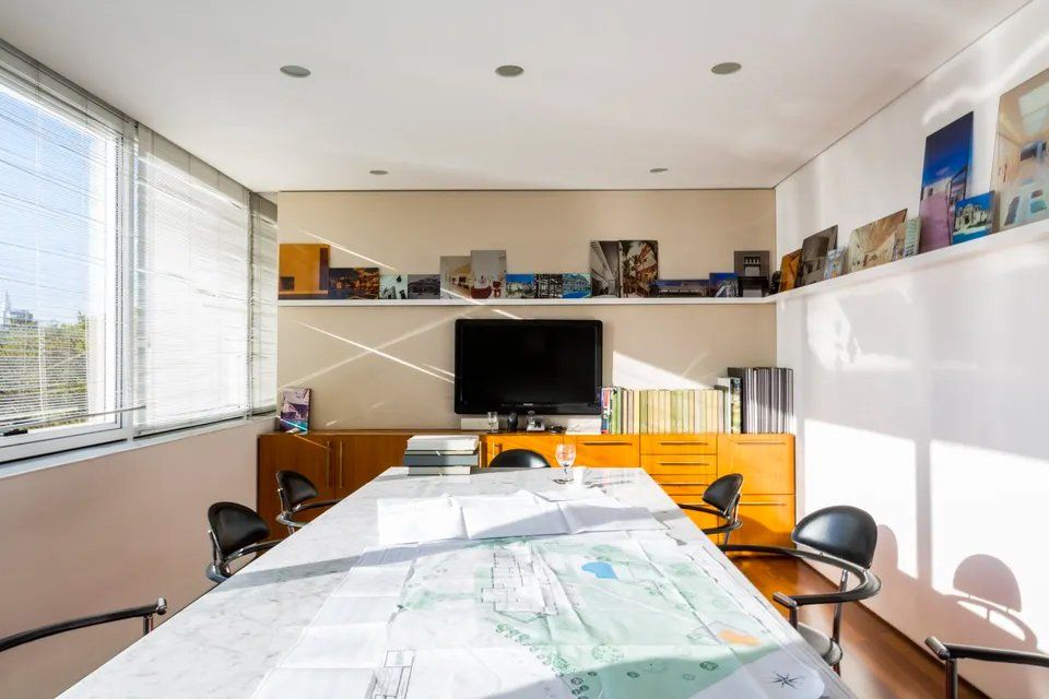 Uma sala de conferências com uma grande mesa e cadeiras e uma TV de tela plana.