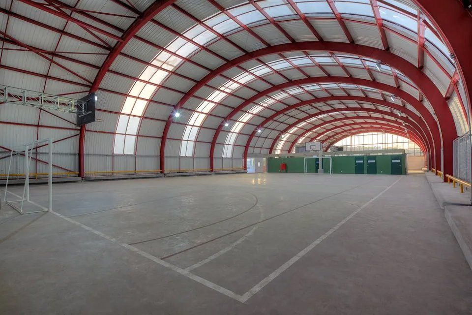 Uma grande quadra de basquete coberta com telhado vermelho