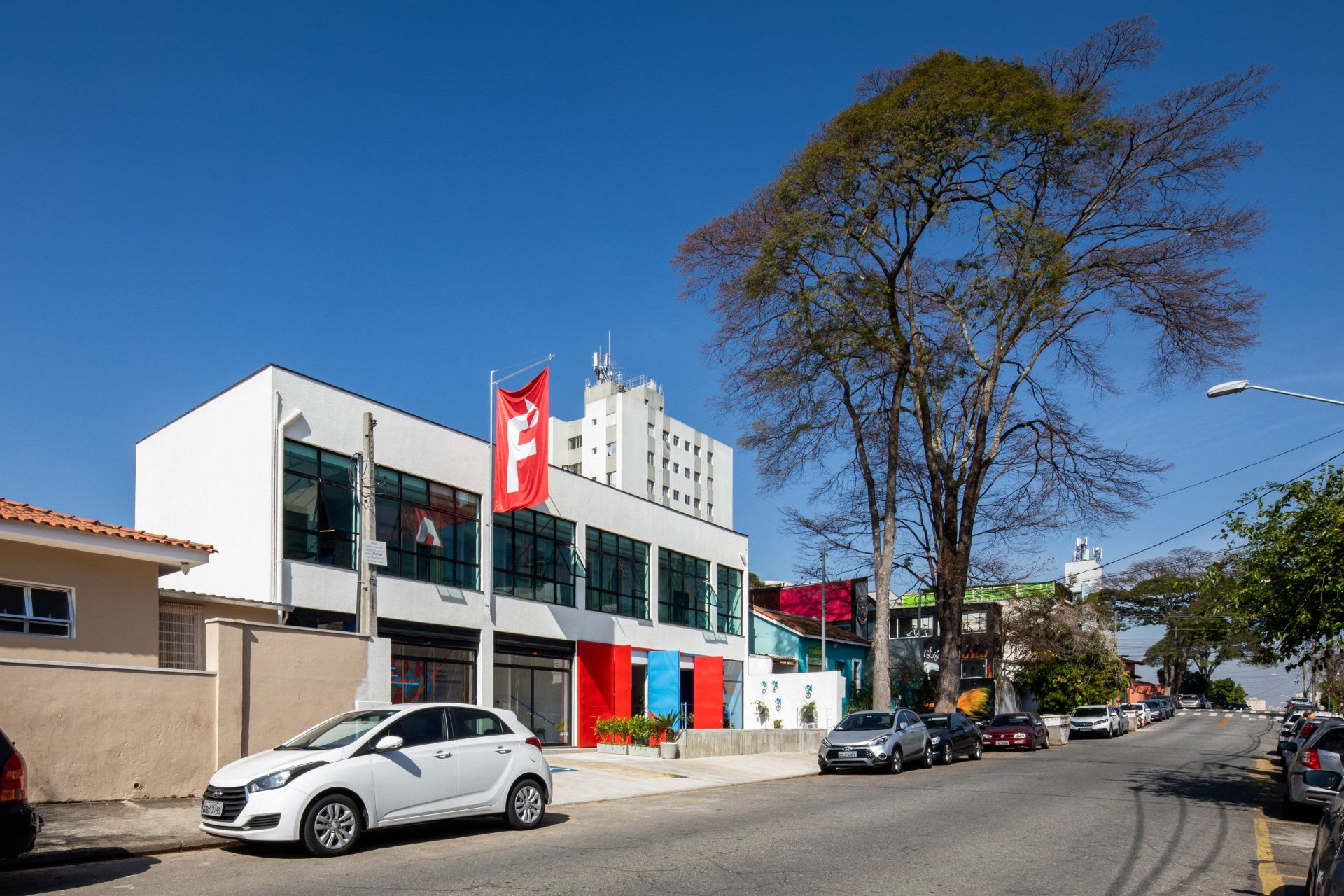 Um carro branco está estacionado em frente a um grande edifício.