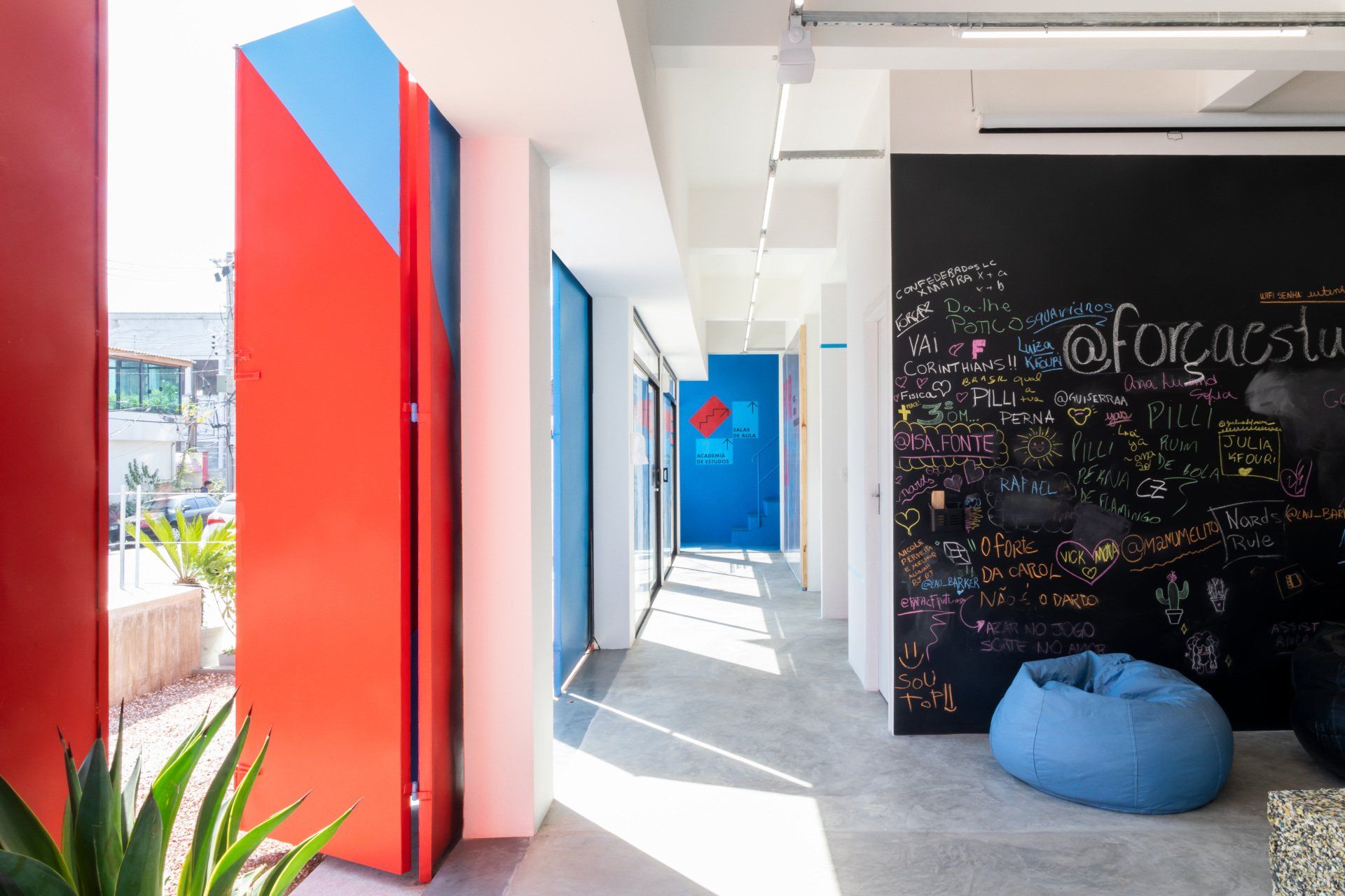 Um corredor com um pufe e um quadro-negro na parede.