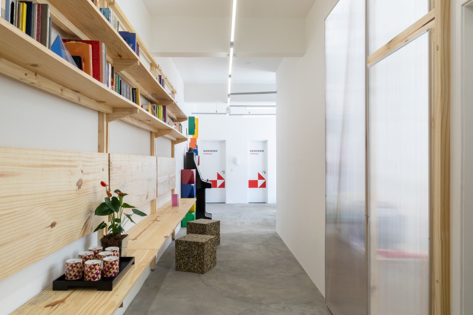 Um corredor com banco de madeira e estantes cheias de livros.