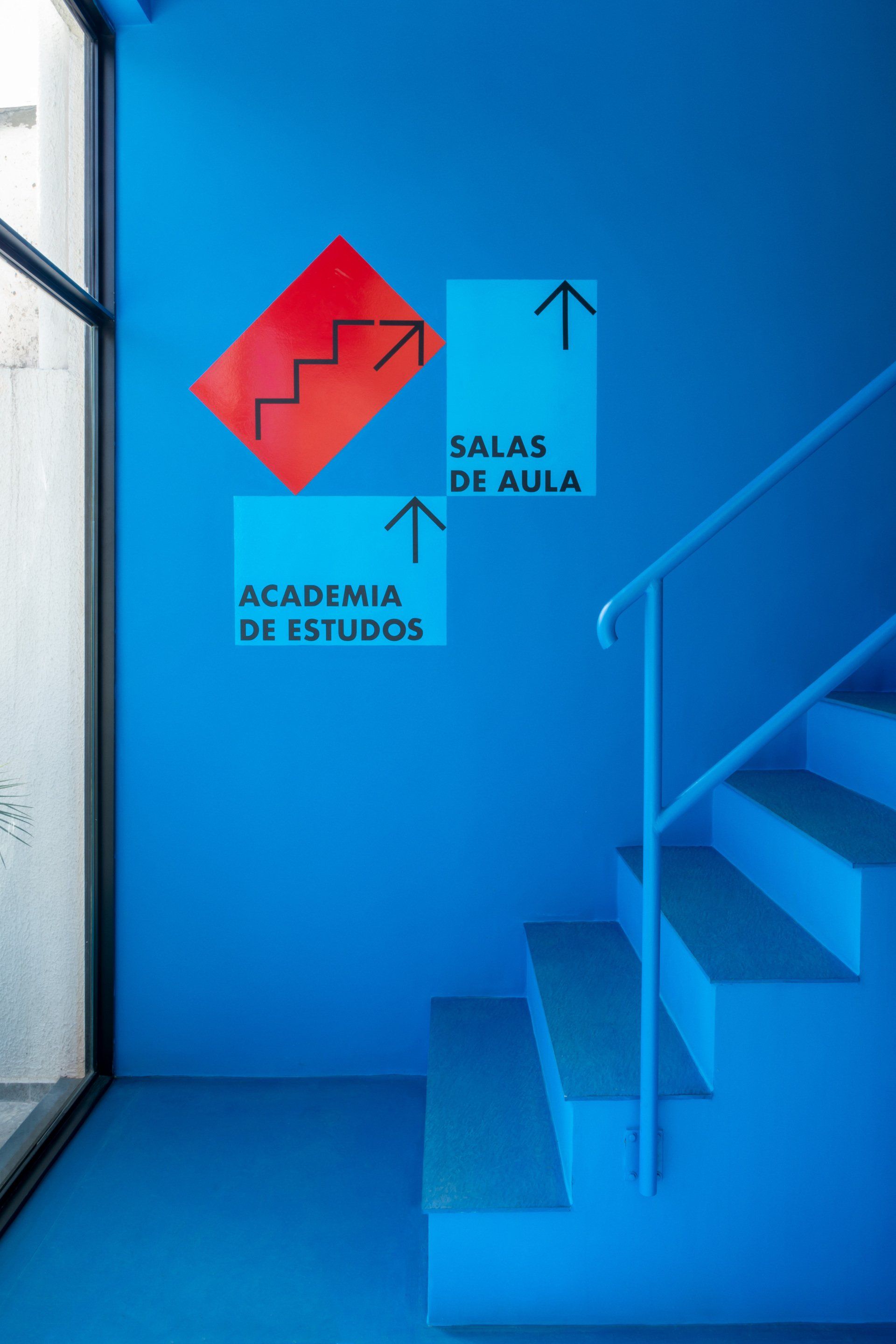 Uma escada azul com uma placa na parede que diz academia de estudos