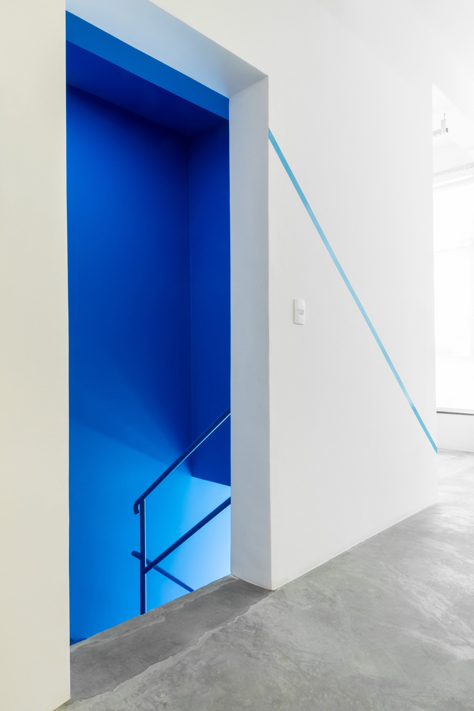 Uma porta azul com um corrimão azul que leva a uma escada