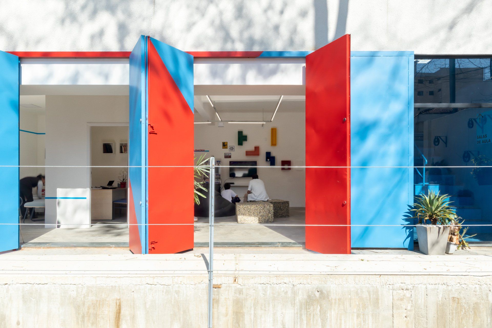 Uma porta vermelha e azul está aberta para uma sala.