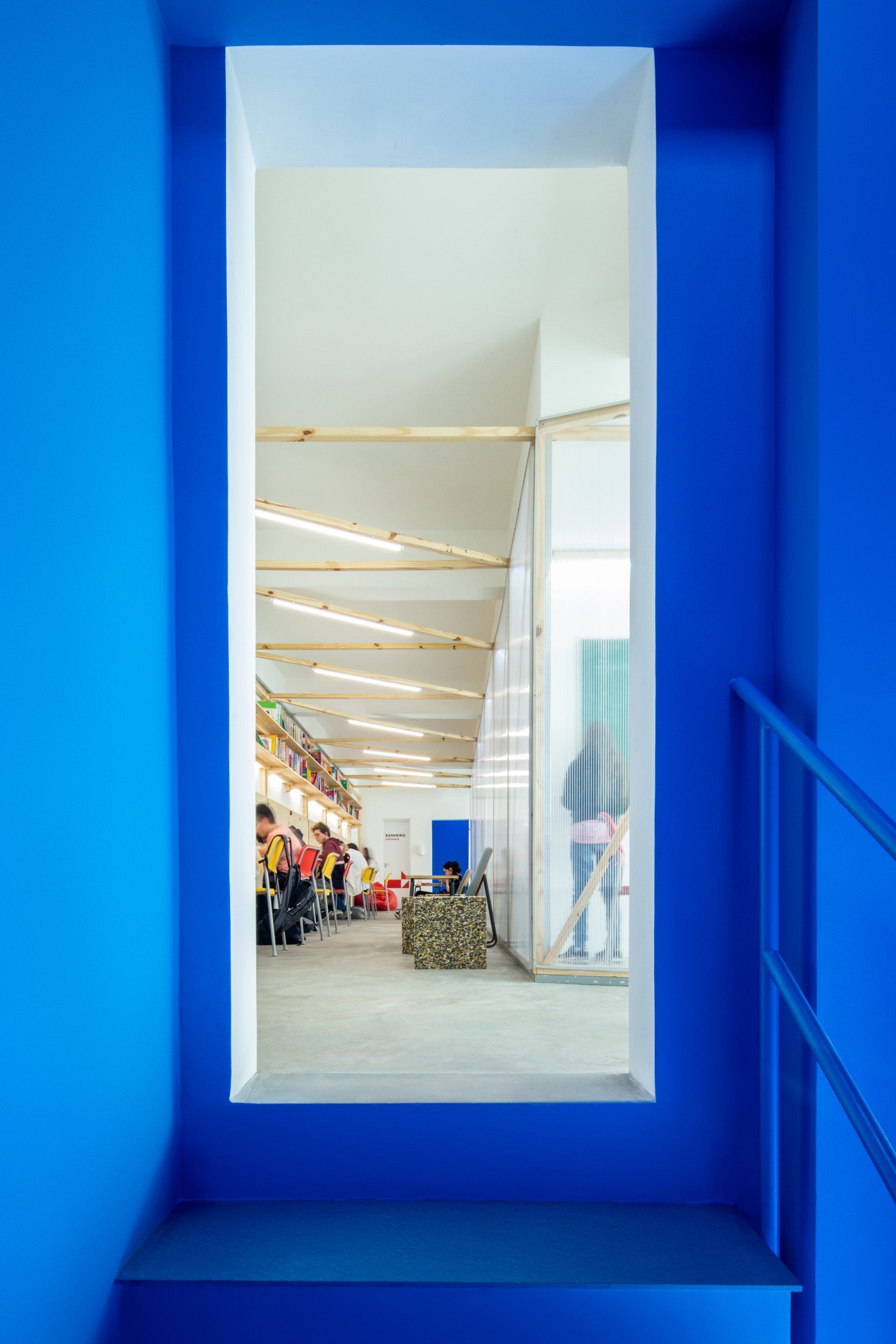 Uma parede azul com uma janela e escadas que levam a uma sala.