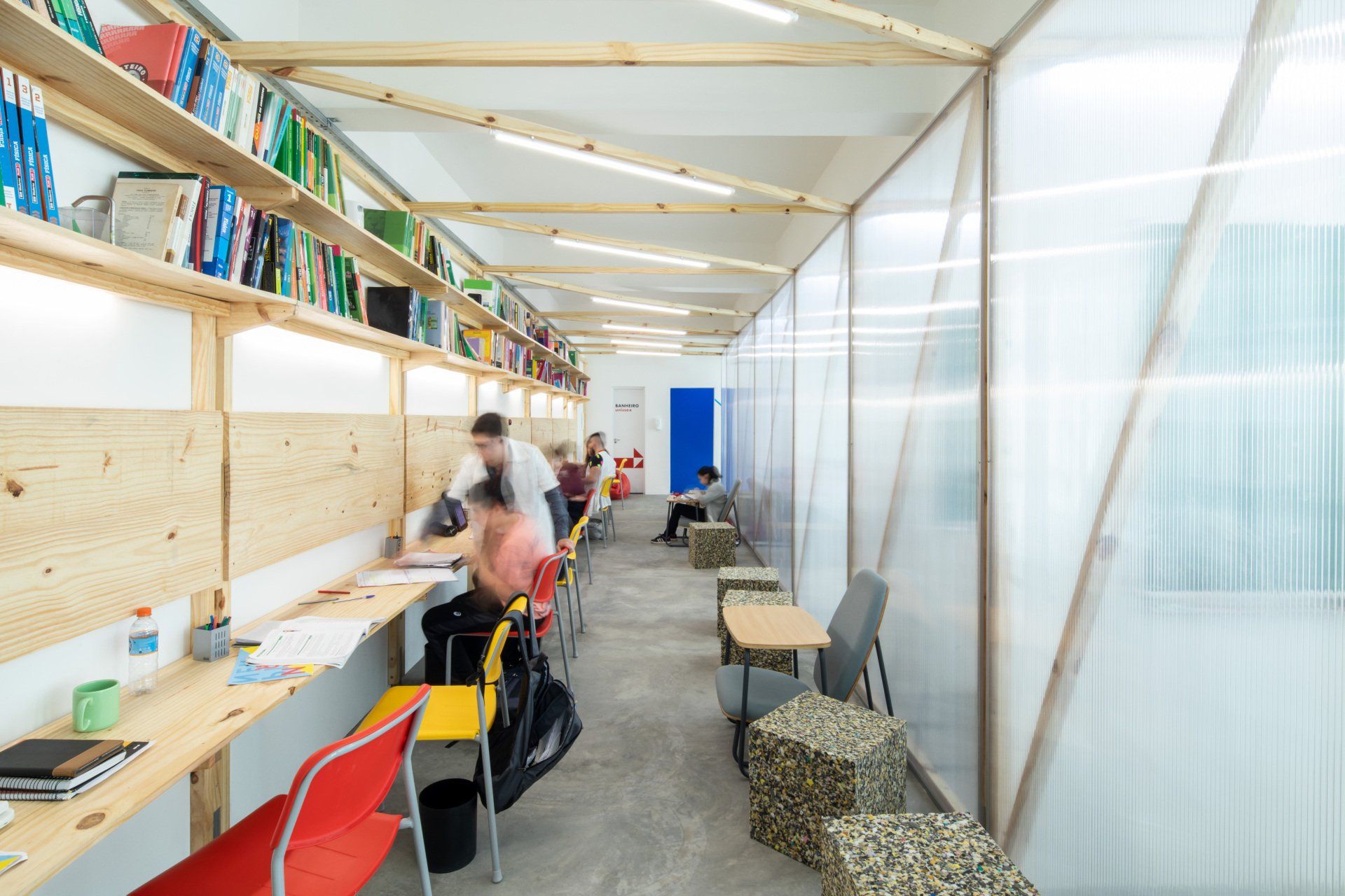 Um grupo de pessoas está sentado em mesas em uma biblioteca.