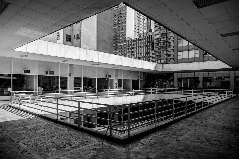 Uma foto em preto e branco de um prédio com uma cerca ao redor