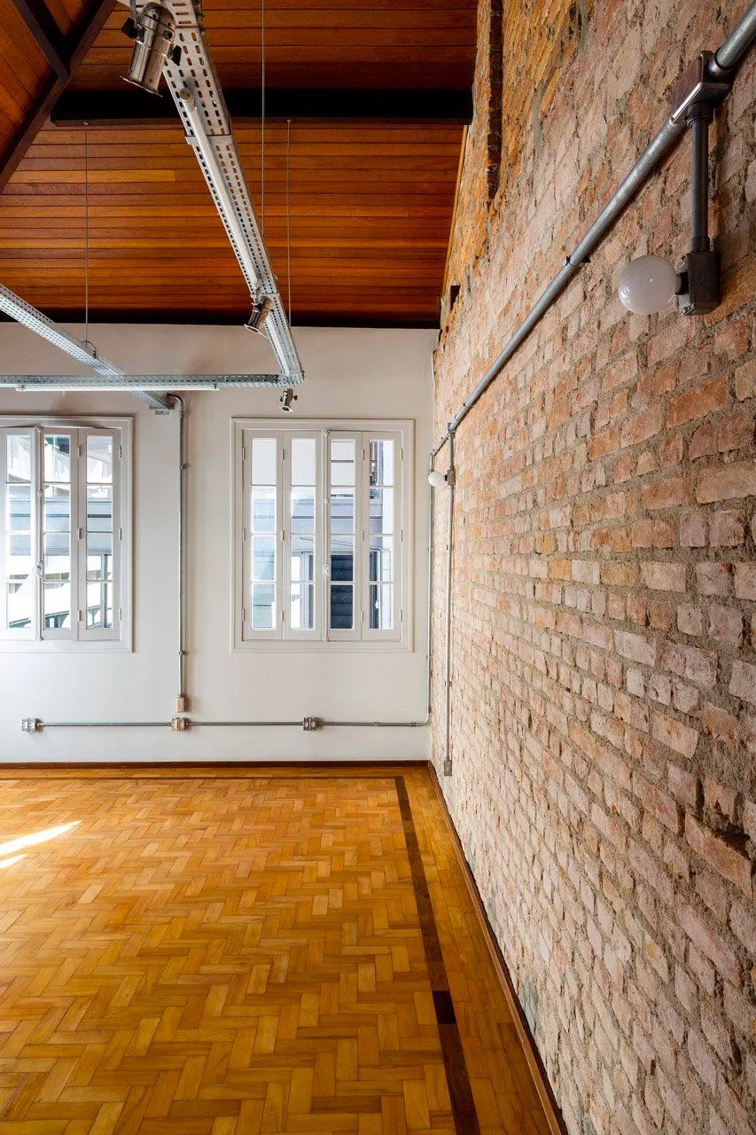 Uma sala vazia com piso de madeira e parede de tijolos.