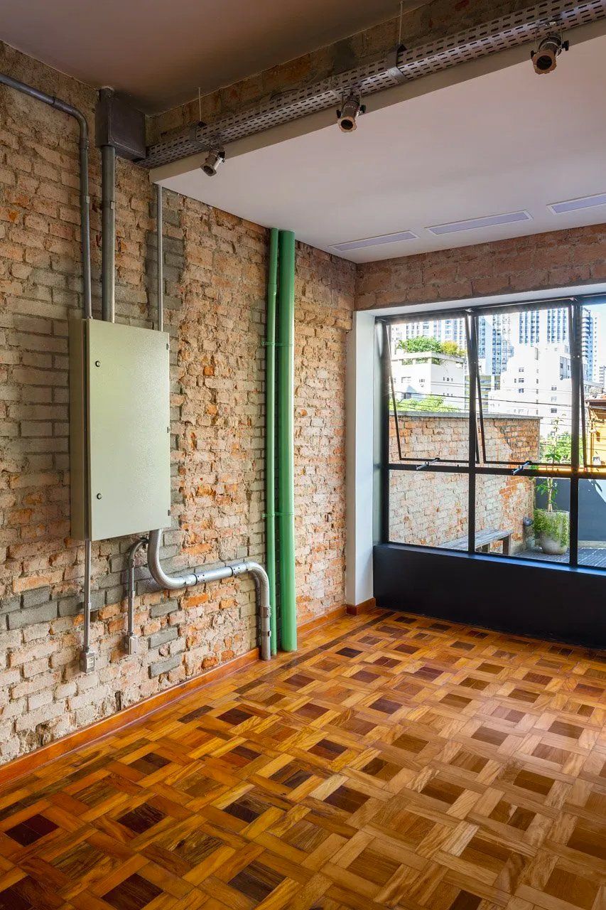 Uma sala vazia com piso de madeira e paredes de tijolos.