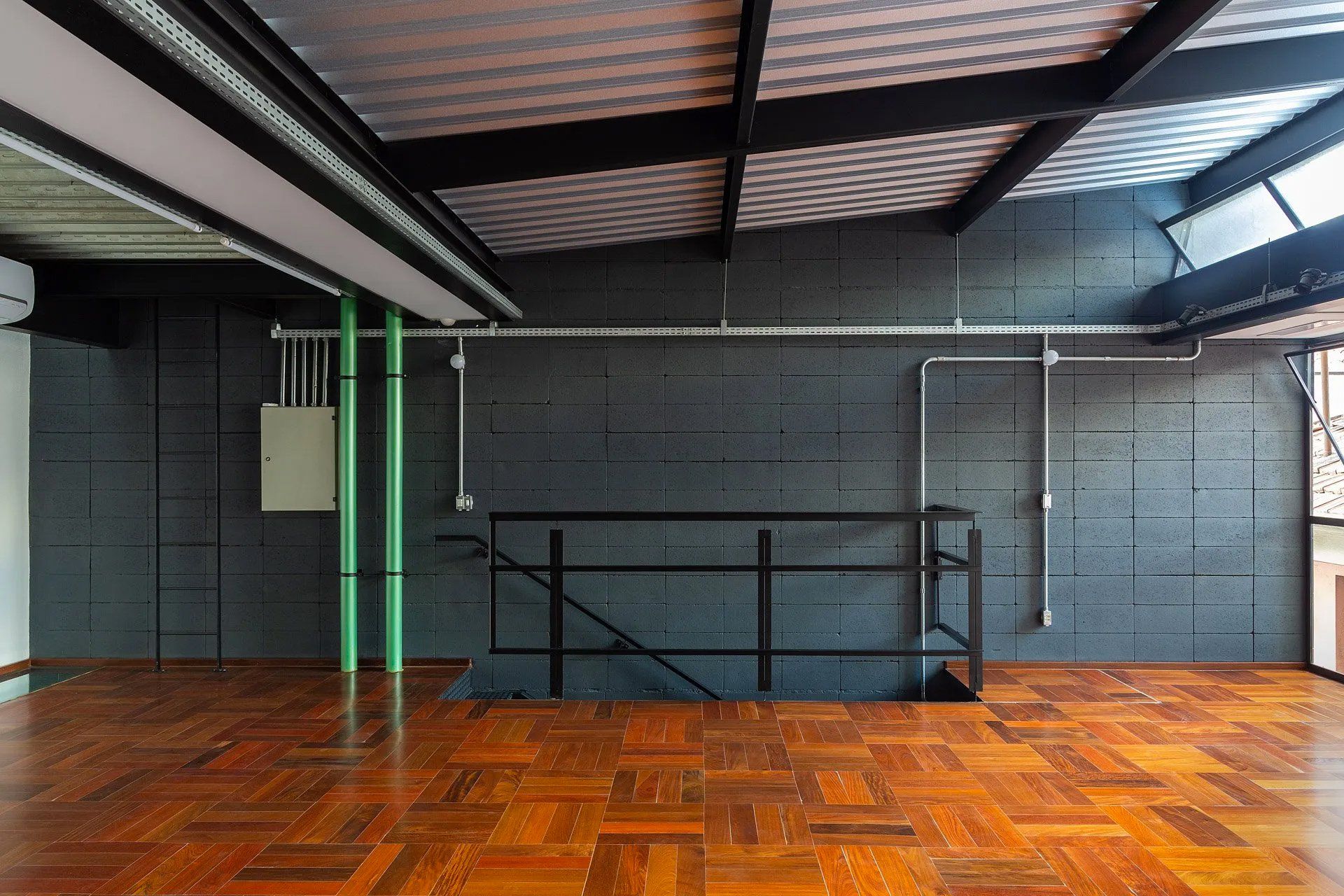 Uma sala vazia com piso de madeira e uma escada.