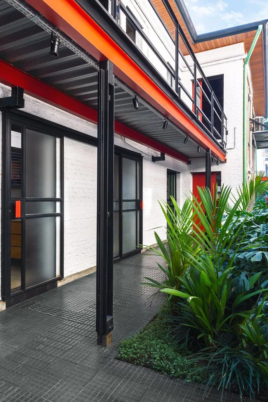 Um prédio com uma passarela coberta e plantas na frente