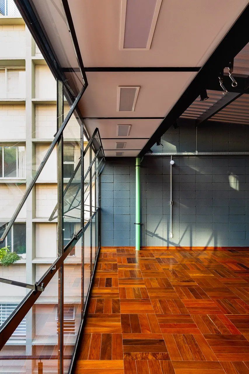 Uma sala vazia com piso de madeira e muitas janelas