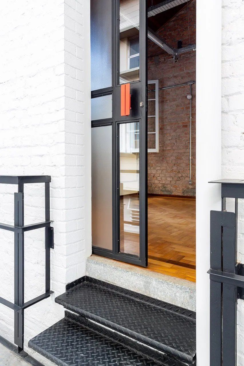 Uma porta com escadas que levam até ela e uma parede de tijolos atrás dela.