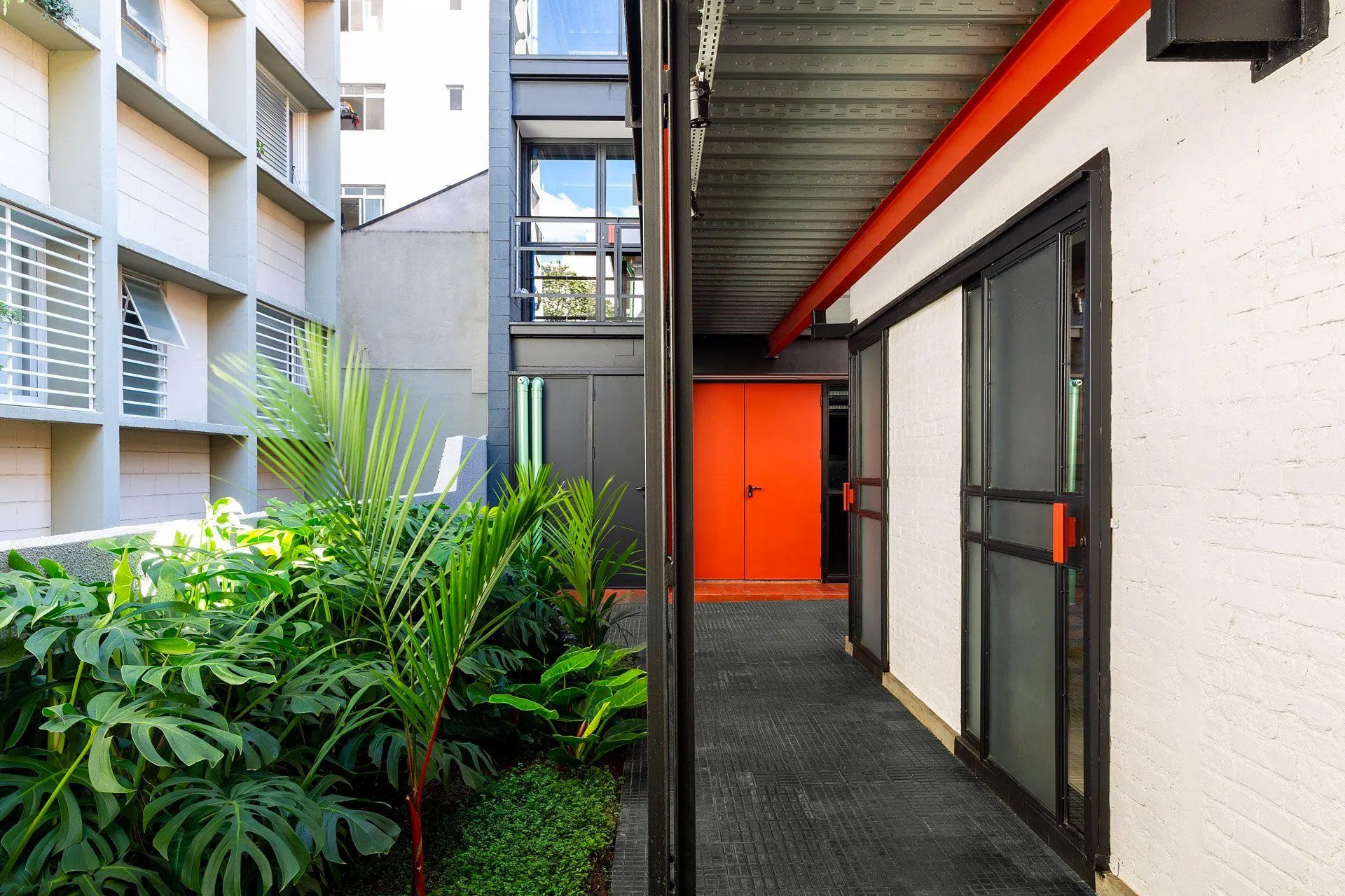 Um corredor entre dois edifícios com uma porta vermelha