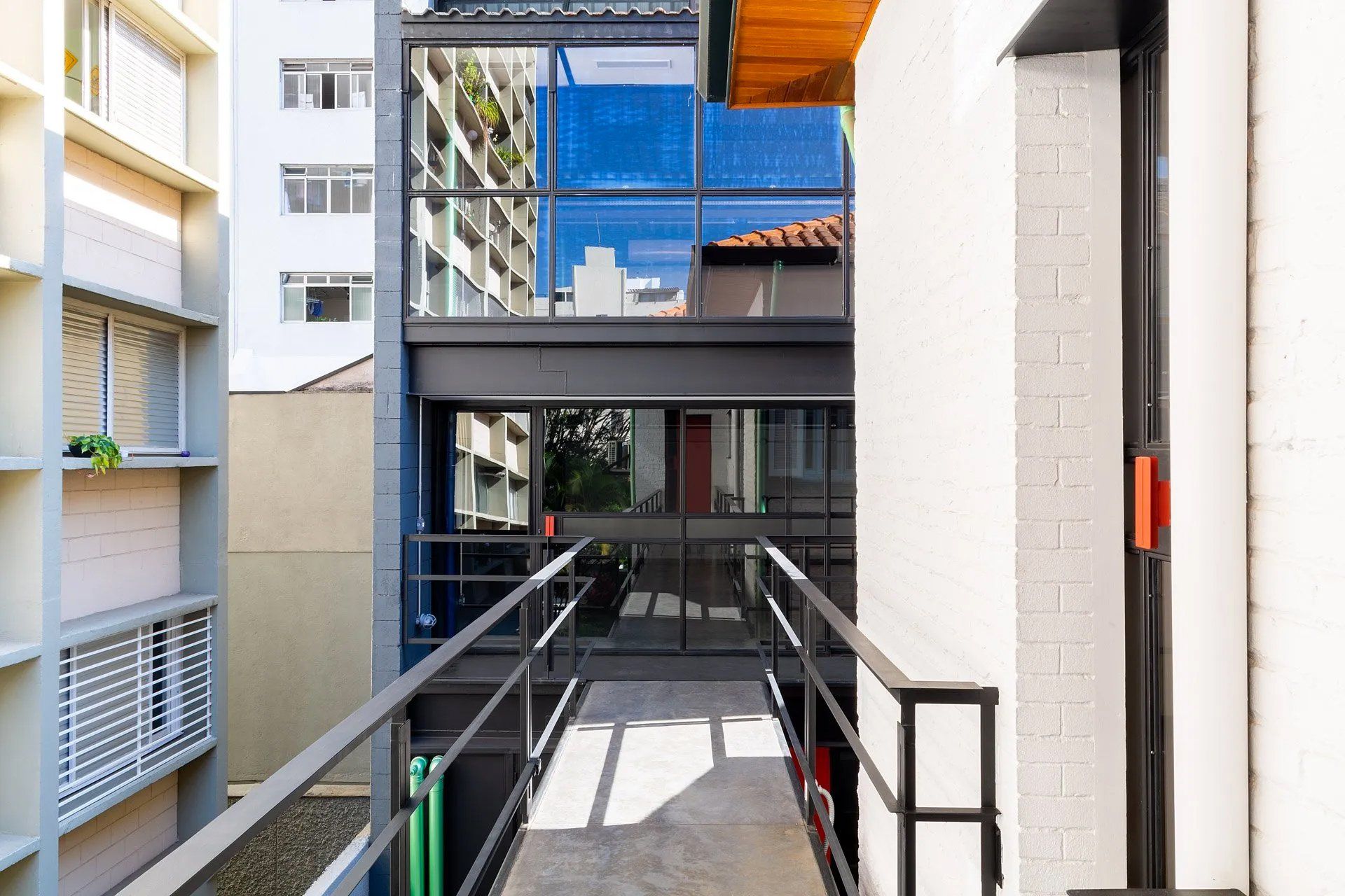 Uma passarela entre dois edifícios com grade e varanda.